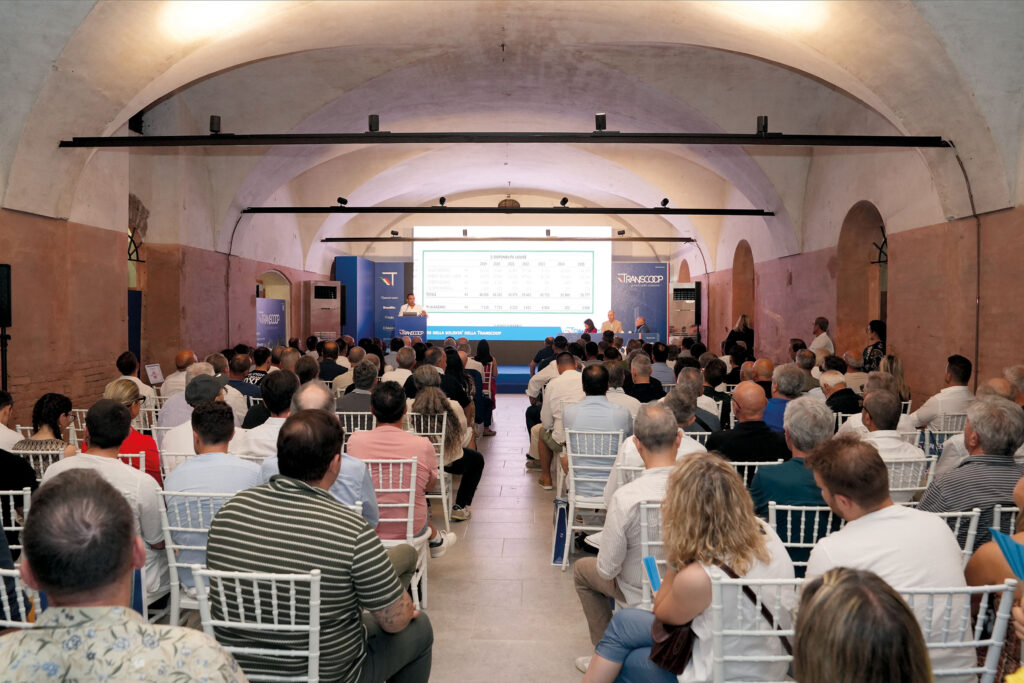 partecipanti all'assemblea di bilancio Transcoop che ascoltano e guardano la presentazione sul palco